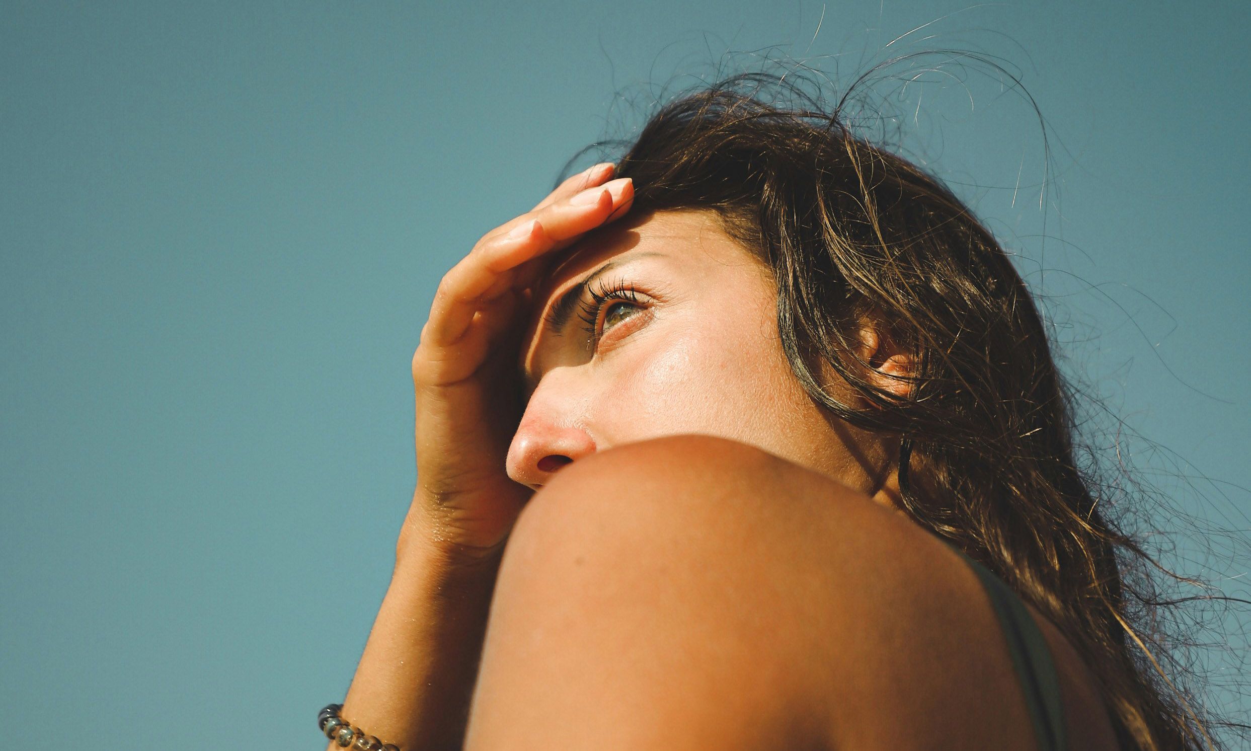 woman at beach covering face from the sun