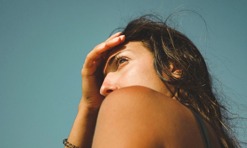 woman at beach covering face from the sun