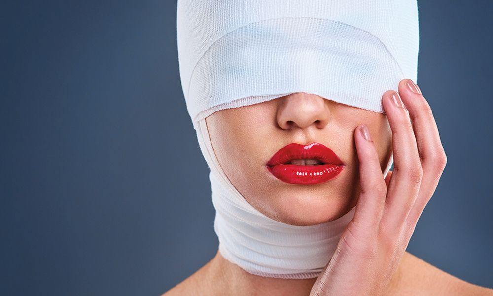 woman with bandages over face and red lipstick