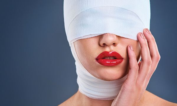 woman with bandages over face and red lipstick