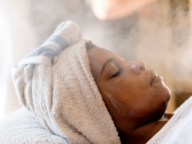 woman with a towel on her head getting a steam facial