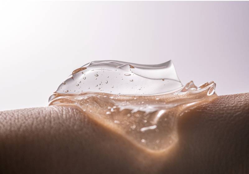 Close-up of a clear, gel-like serum with air bubbles resting on textured skin, illustrating a lightweight, hydrating skincare formula