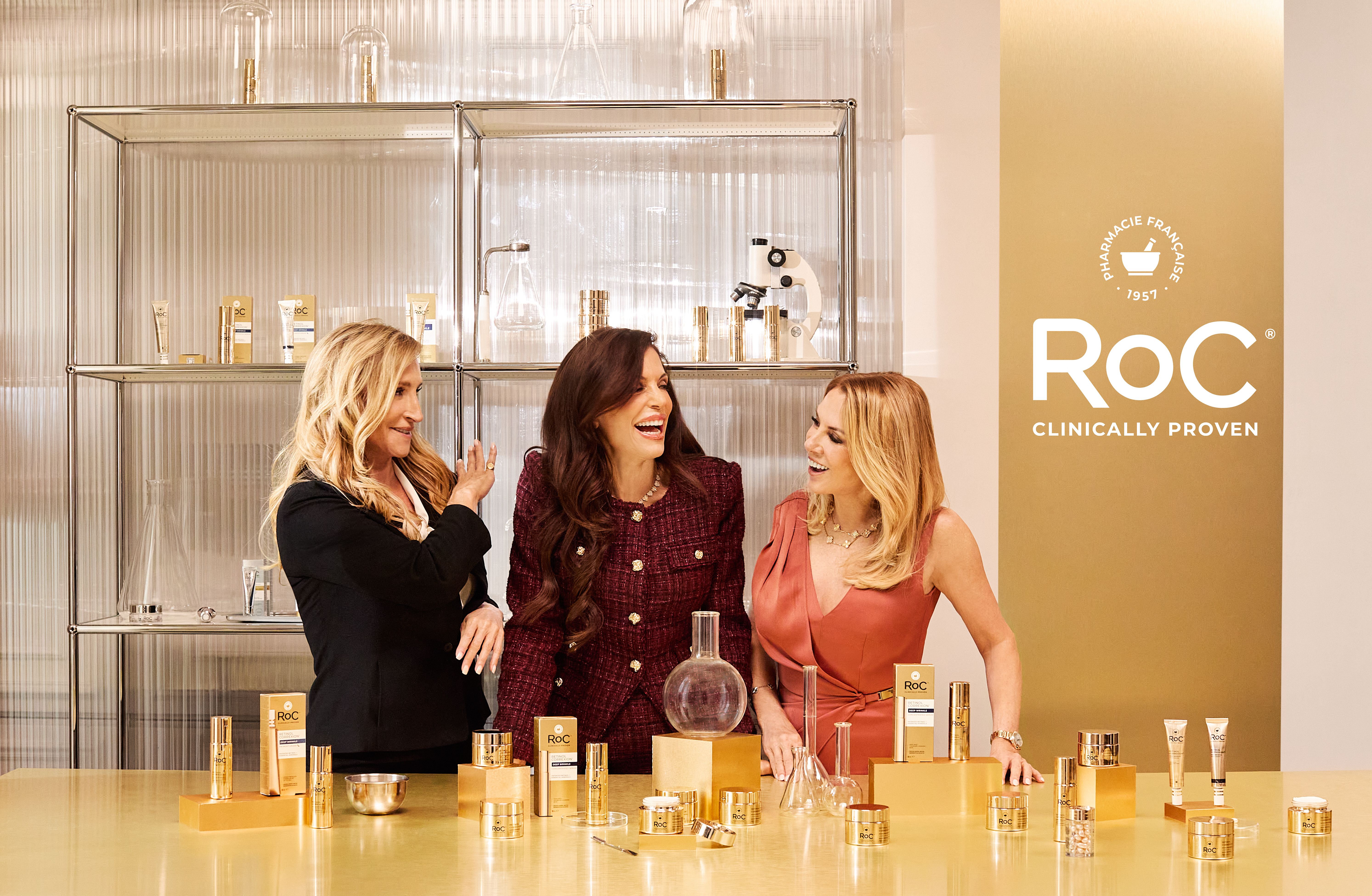 Bethenny Frankel, Sonja Morgan and Ramona Singer pose together at a lab-style setup surrounded by RoC skin-care products during their campaign shoot.