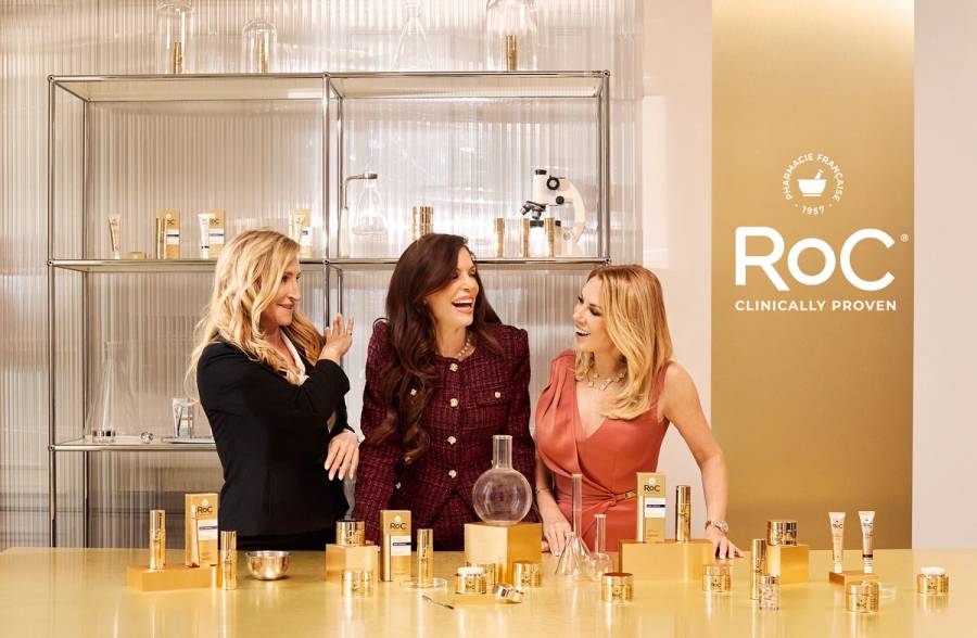 Bethenny Frankel, Sonja Morgan and Ramona Singer pose together at a lab-style setup surrounded by RoC skin-care products during their campaign shoot.