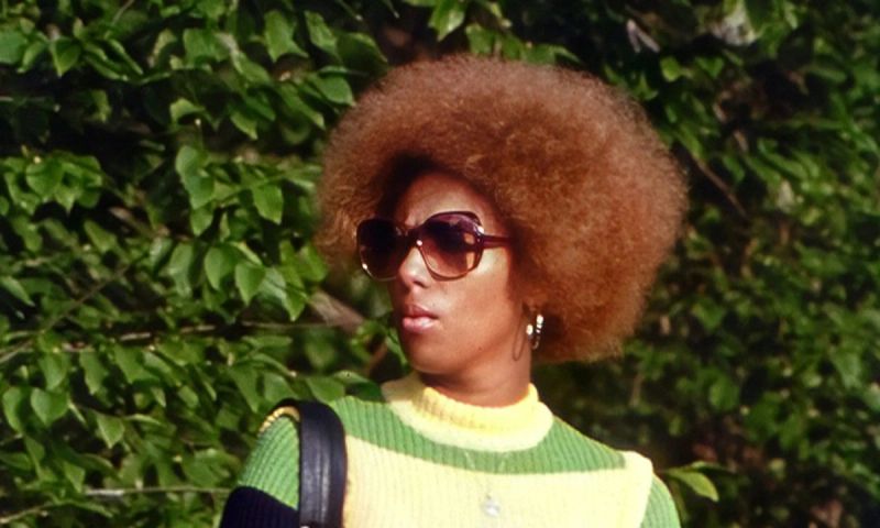 a woman with an afro holding a newspaper