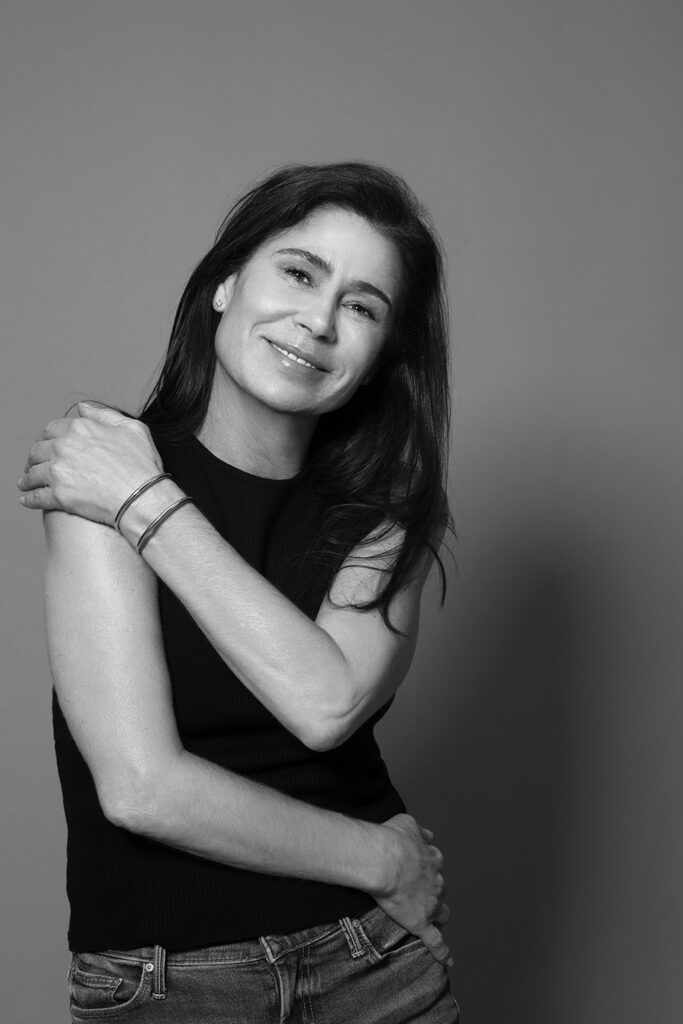 Black and white photo of Maura Tierney wrapping arms around