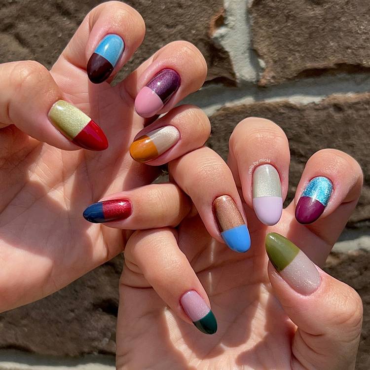 Hands with colorful pill-box-inspired color-block nails featuring metallic finishes, pastel tips and jewel-tone accents in the sun.