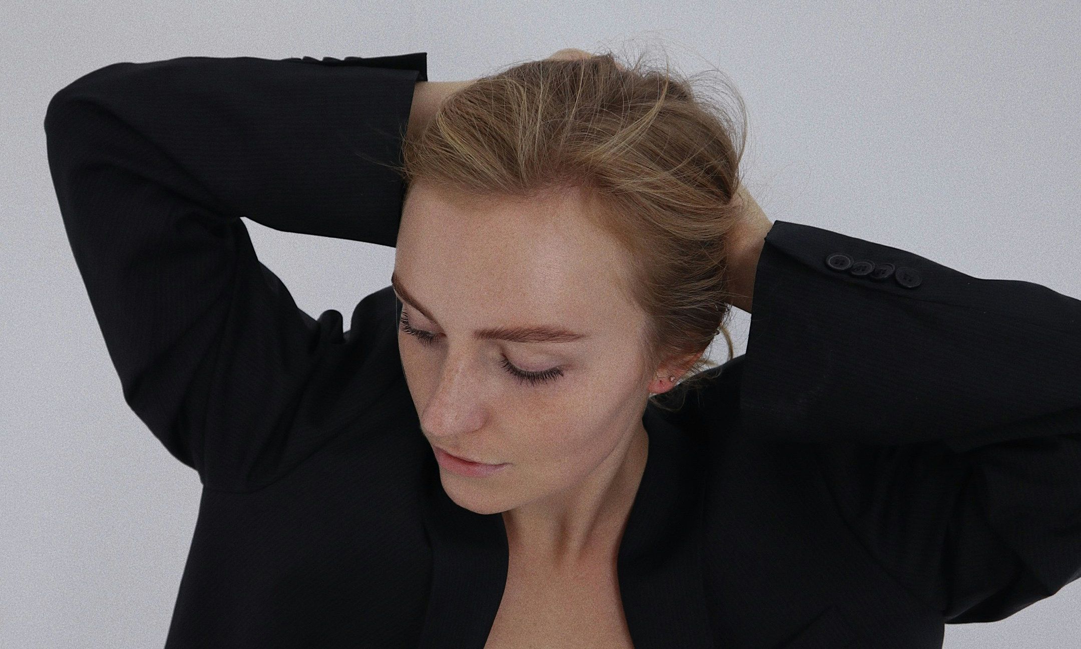 woman in black blazer putting her hair back