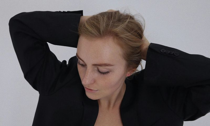 woman in black blazer putting her hair back