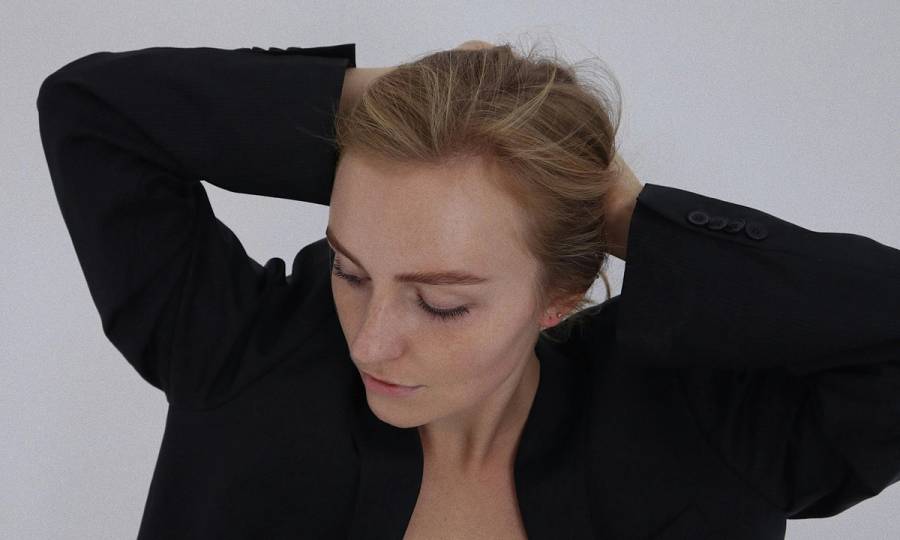 woman in black blazer putting her hair back