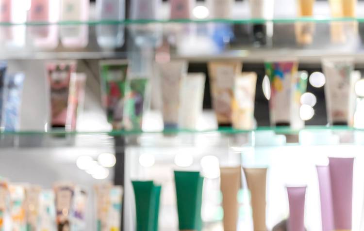 Blurred display of colorful skin-care and beauty products arranged on glass shelves in a retail store