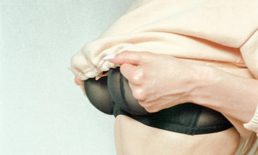 woman lifting up her shirt revealing black bra
