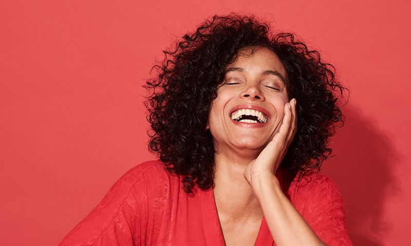 Close-up of a mature woman smiling against a red background