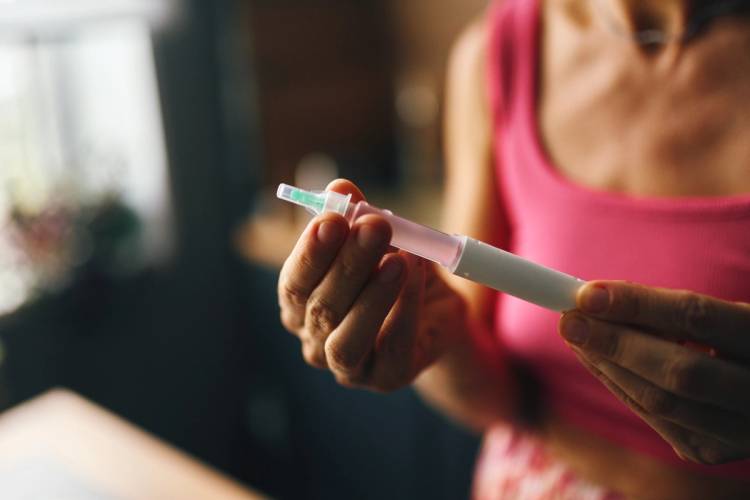 Person holding an insulin pen, preparing to inject medicine