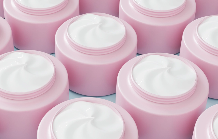 Rows of open pink skin-care jars filled with white cream, shown in close-up