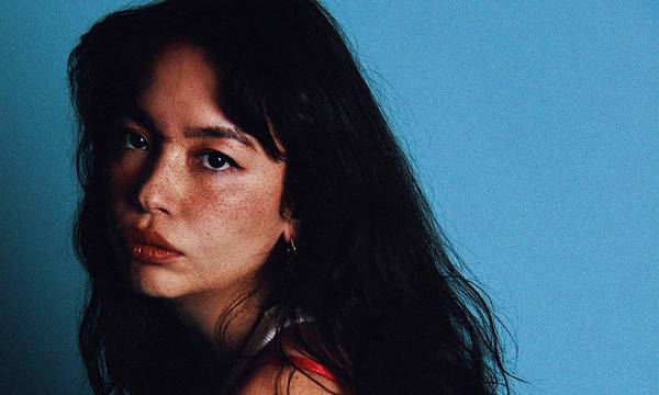 woman with freckles posing against a blue background