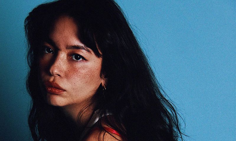 woman with freckles posing against a blue background