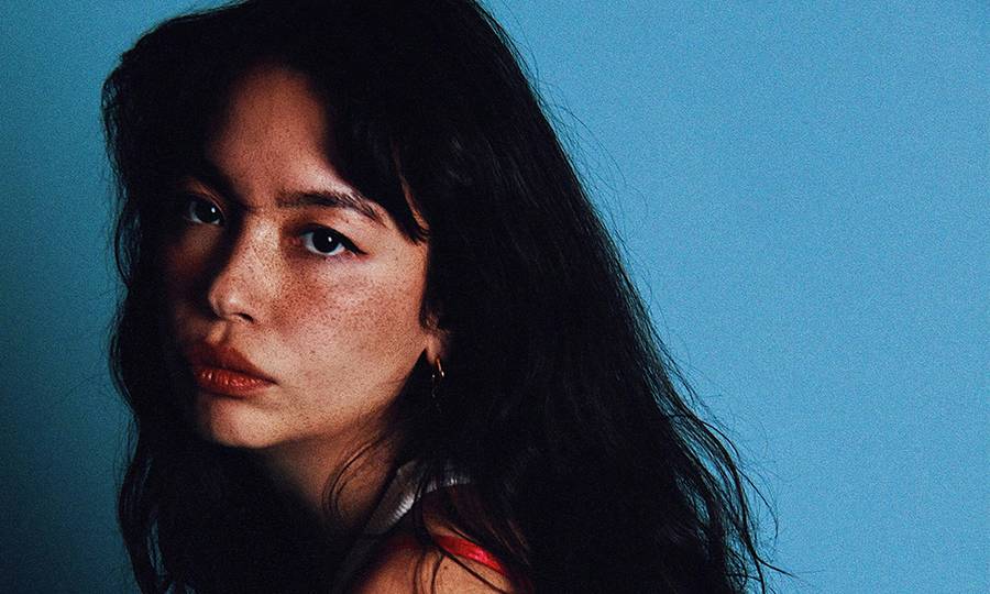 woman with freckles posing against a blue background