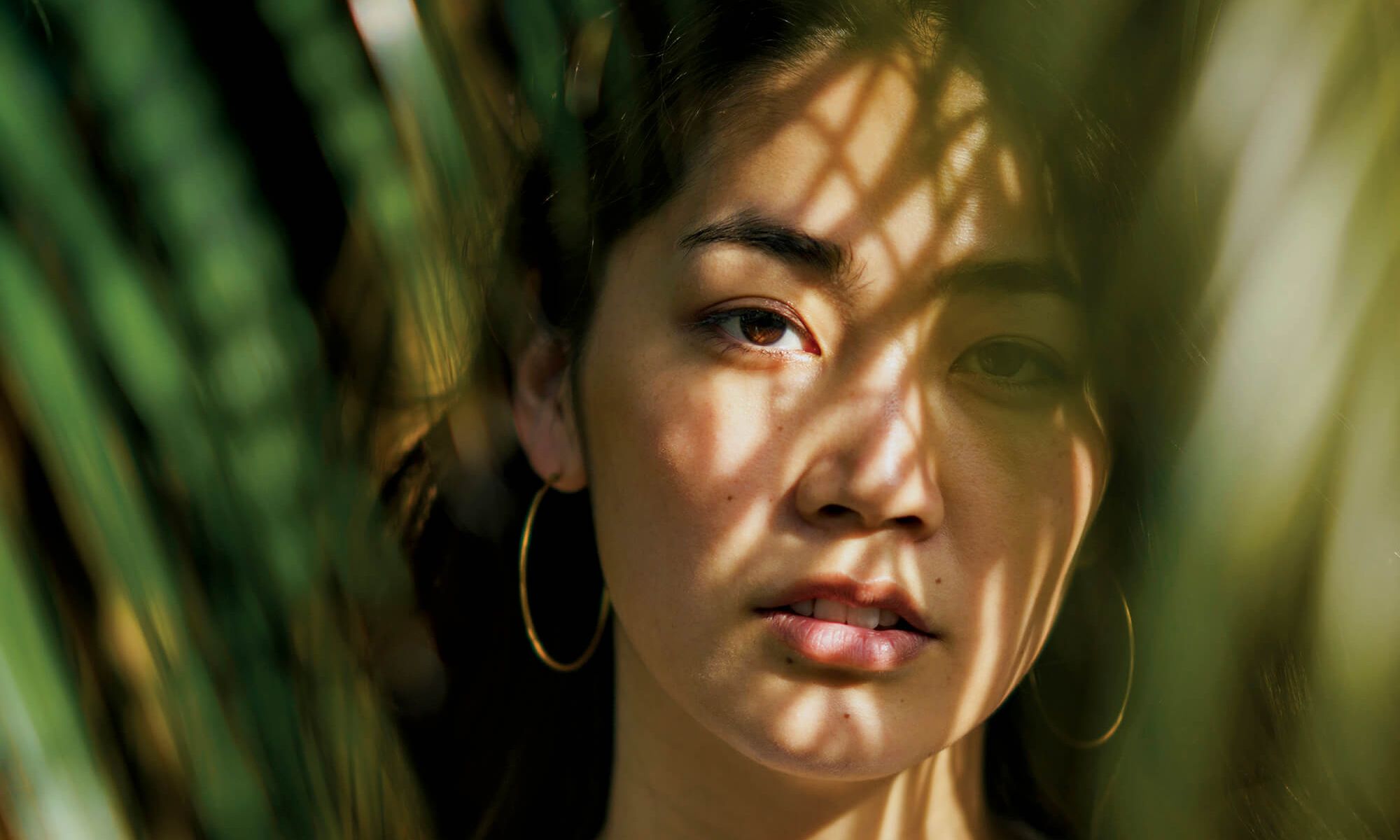 asian woman in shadows of palm trees