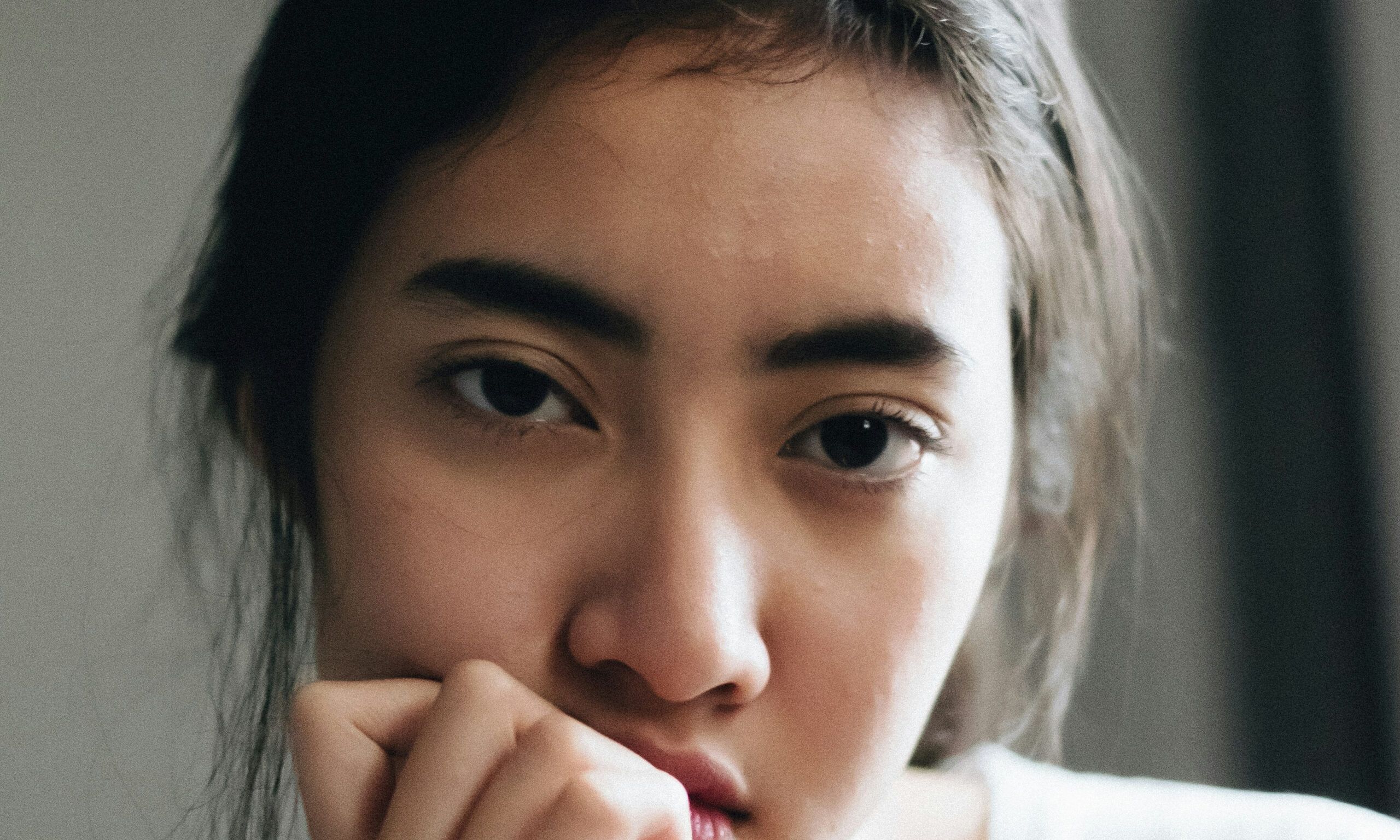 woman looking gloomily with hand at mouth