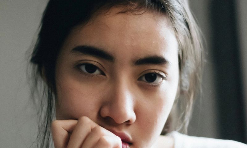 woman looking gloomily with hand at mouth