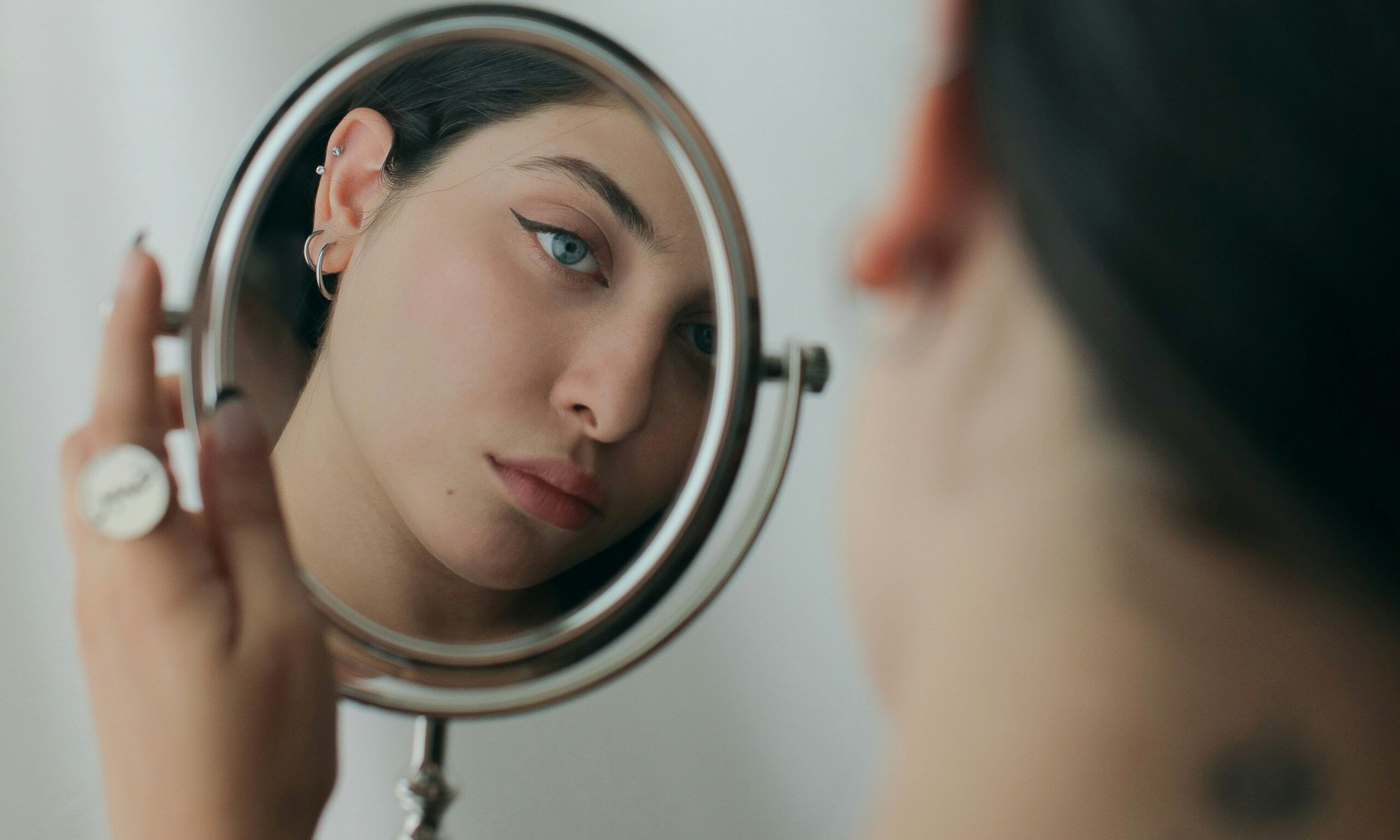 woman looking at her face in a mirror