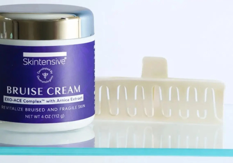 A jar of Skintensive Bruise Cream with EXO-ACE Complex and arnica extract next to a white hair claw clip on a glass shelf.