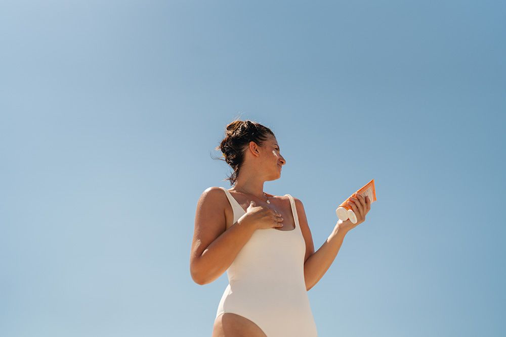 woman applying sunscreen to face and body