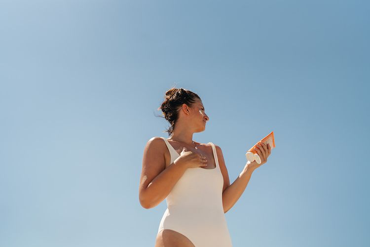 woman applying sunscreen to face and body
