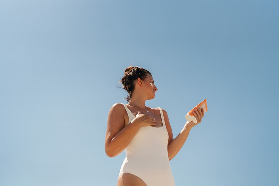 woman applying sunscreen to face and body