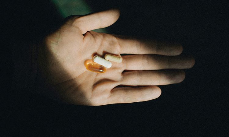 hand holding supplements in shadows