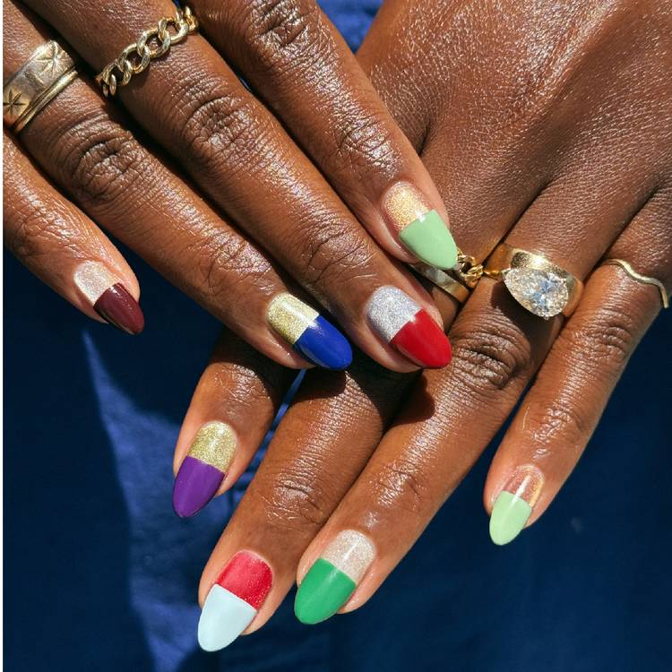 Hands with colorful pill-box-inspired nails featuring metallic bases and bold red, blue, green, purple and mint rounded tips.