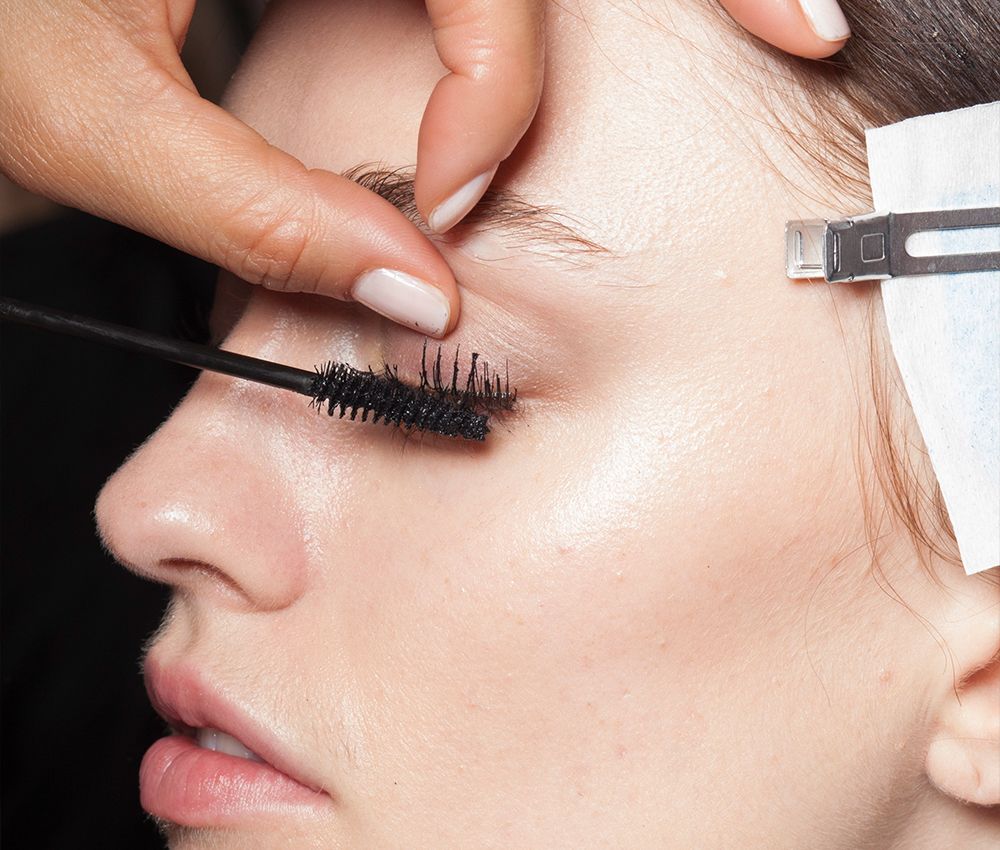 Woman getting her mascara applied by a makeup artist