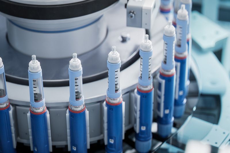 Close-up of Medical Injector on Conveyor Line during Production Process at Modern Pharmaceutical Factory. Medical Drug Production Plant. Weight Loss Medication Manufacturing.