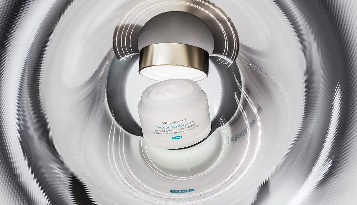 Woman applying moisturizer to her face in front of a mirror, illustrating a barrier-supporting skin-care routine to reduce retinoid irritation and support healthy skin.