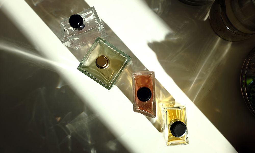 four perfume bottles on white background, seen in a sunlight and shadows