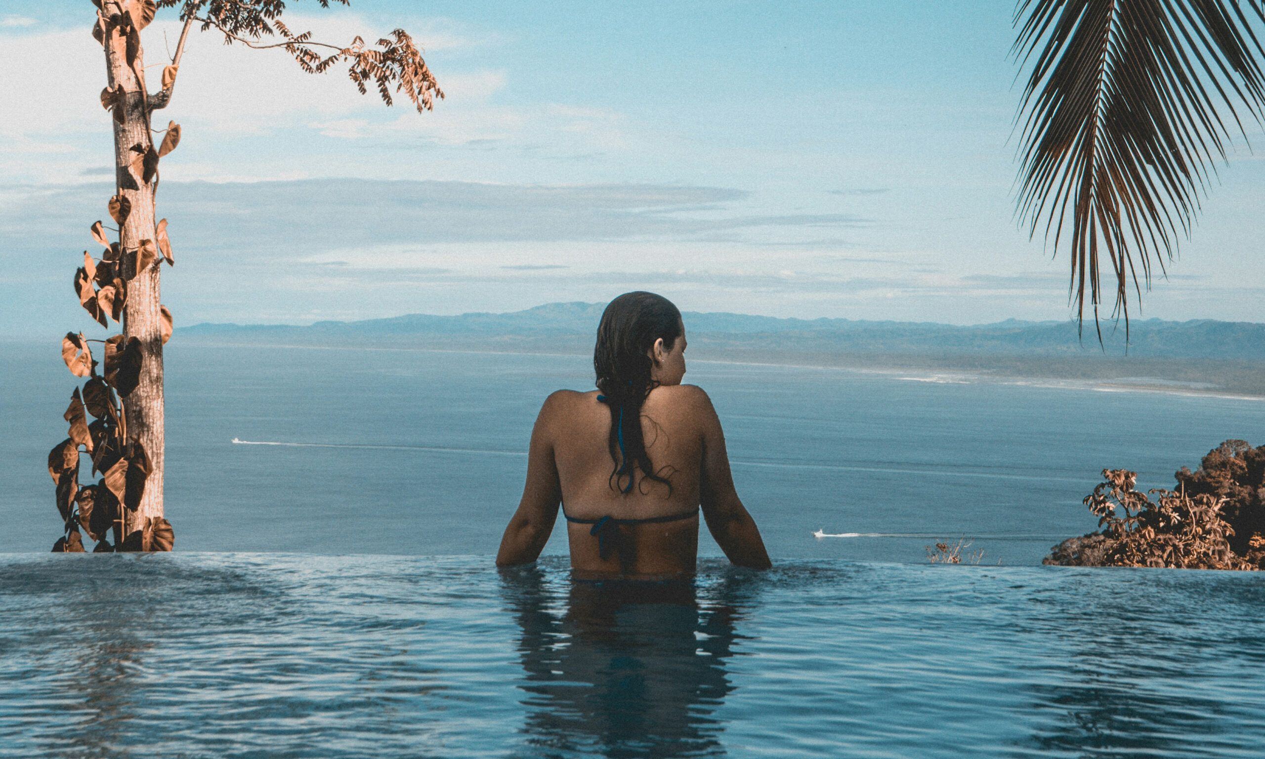 back view of woman in infinity pool looking out over ocean