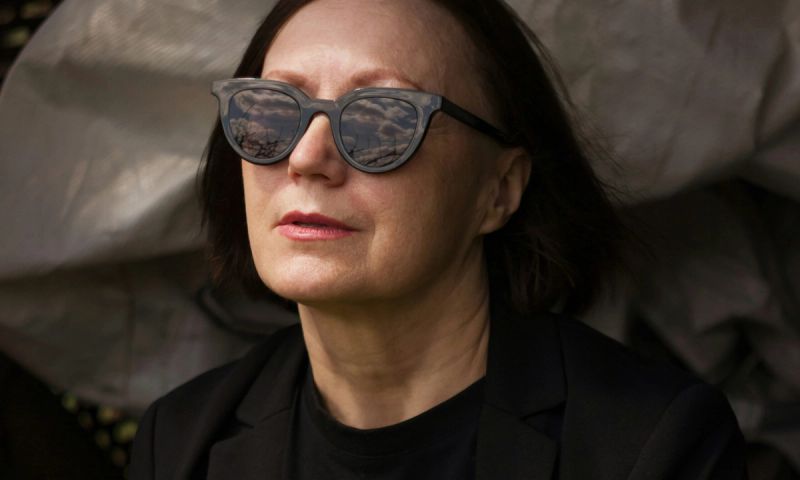 middle aged woman in sunglasses sitting outdoors