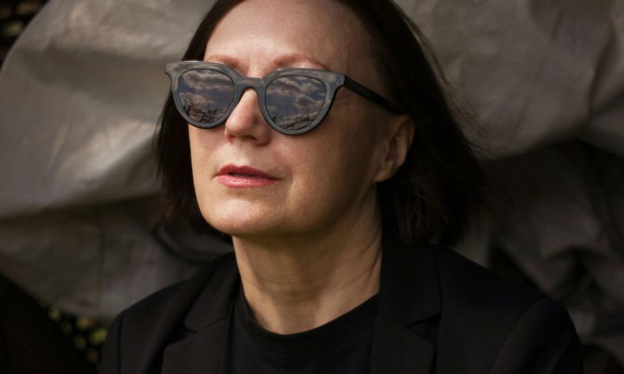 middle aged woman in sunglasses sitting outdoors