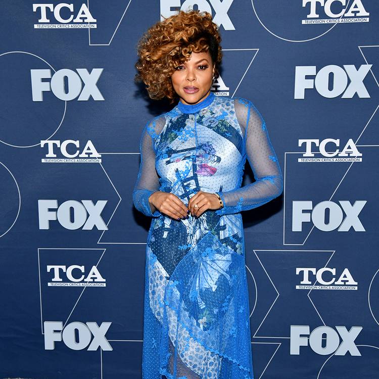 Taraji P. Henson with short curly hair and wearing a full-length blue dress posing on red carpet