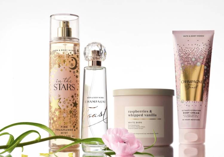 Bath & Body Works fragrance mist, perfume, candle and body cream products arranged with a pink flower on a white background