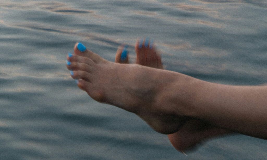 close up of woman's bare feet against a body of water