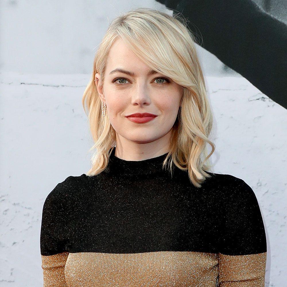 Emma Stone with blonde hair wearing a gold and black turtleneck