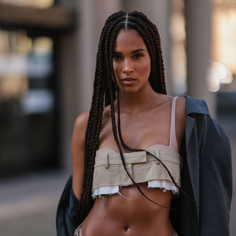 Woman with long box braids in crop top and off-the-shoulder jacket