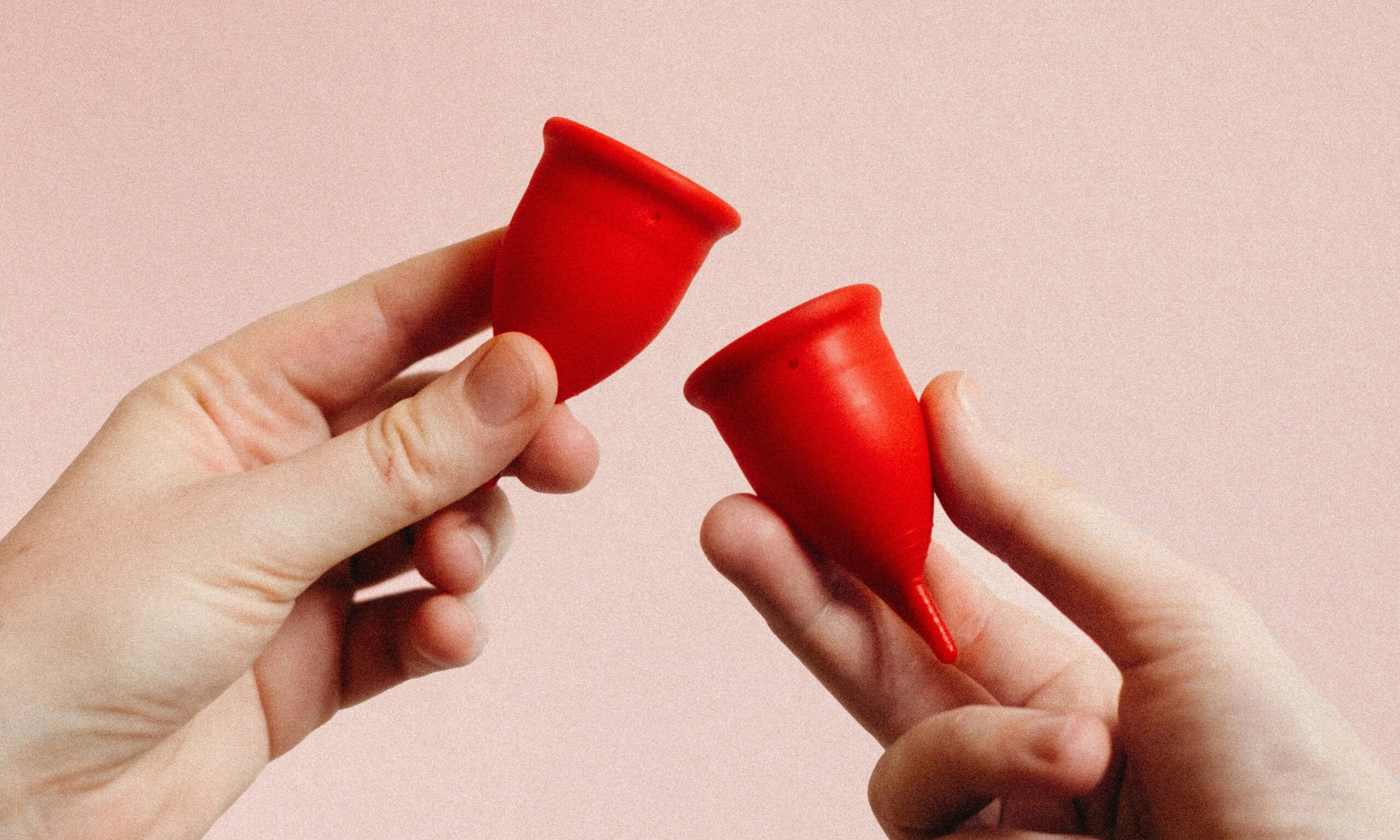 hands holding two red diva cups