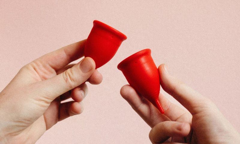 hands holding two red diva cups