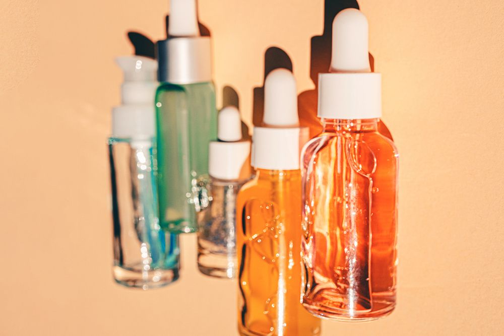 Assorted glass bottles with cosmetic liquids, serum or gel. Vibrant trendy background of cosmetic products