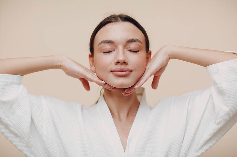 woman with eyes closed and hands on chin