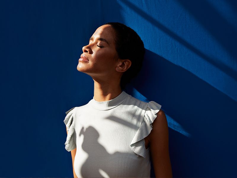 woman looking into sun on blue background