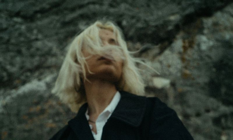 woman with short platinum blonde hair outside in black coat